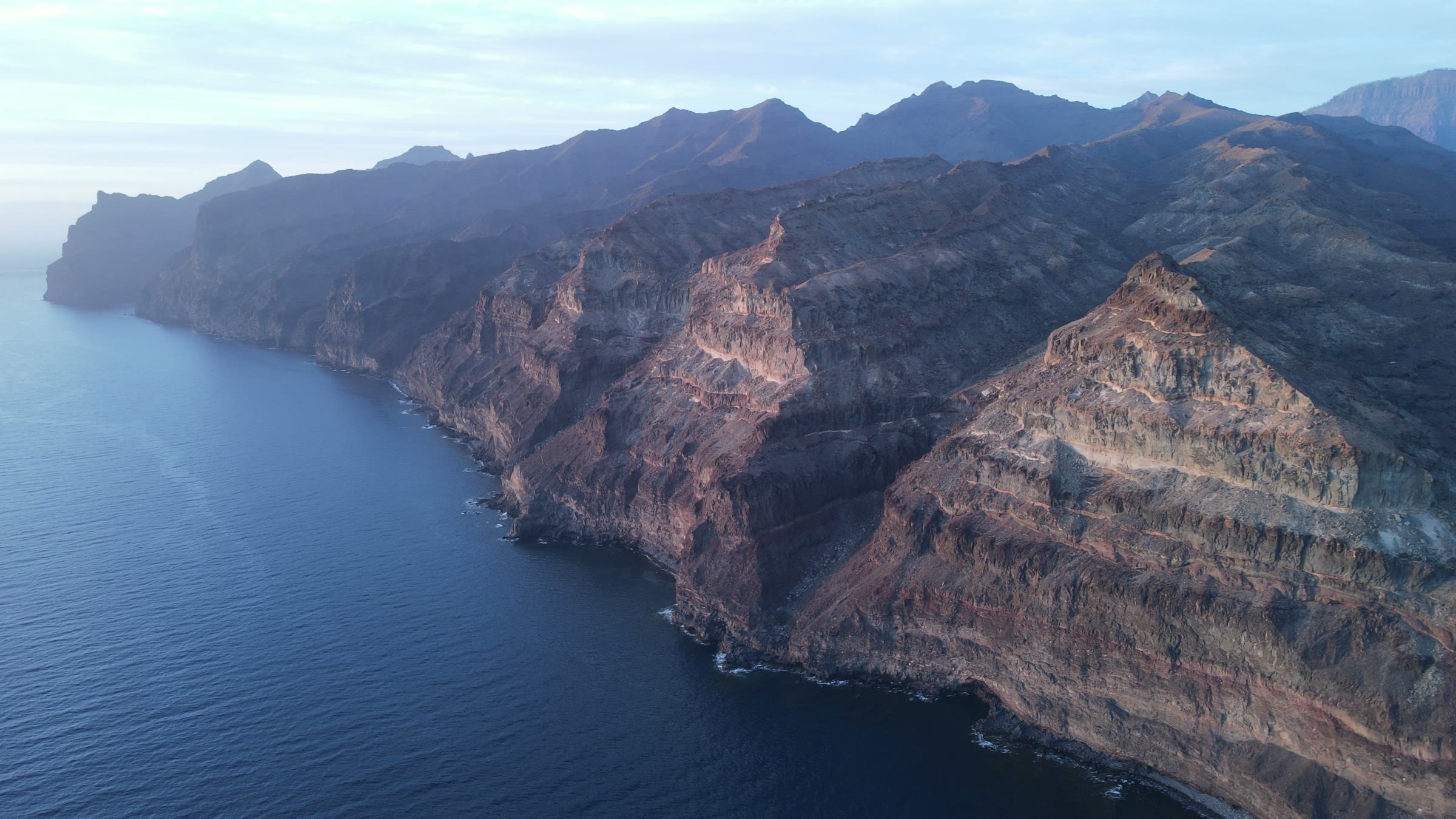 Survol des falaises volcaniques des Îles Canaries au coucher du soleil